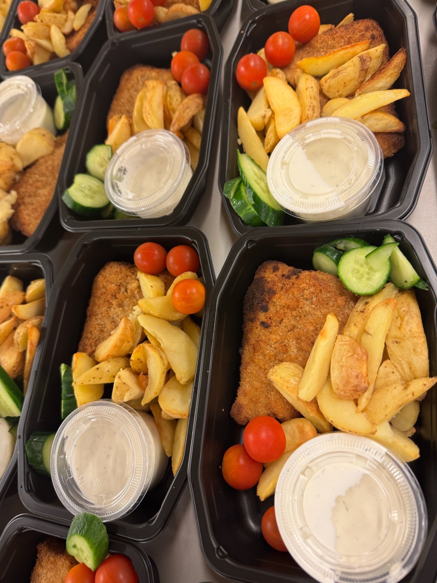 Matlådor med panerad schnitzel, klyftpotatis, gurka och tomat
