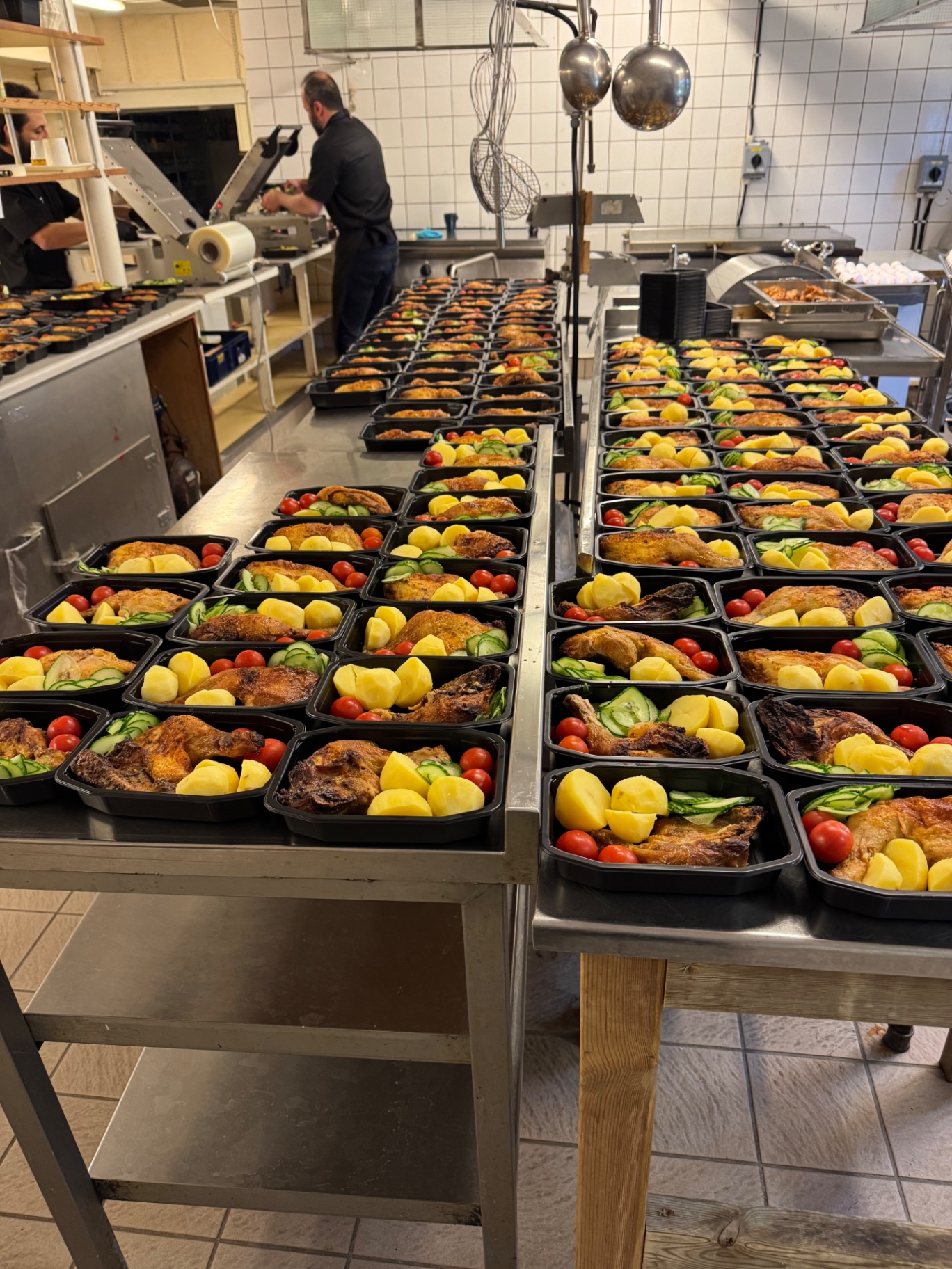 Hundratals matlådor med kyckling, potatis och grönsaker packade i produktionsköket
